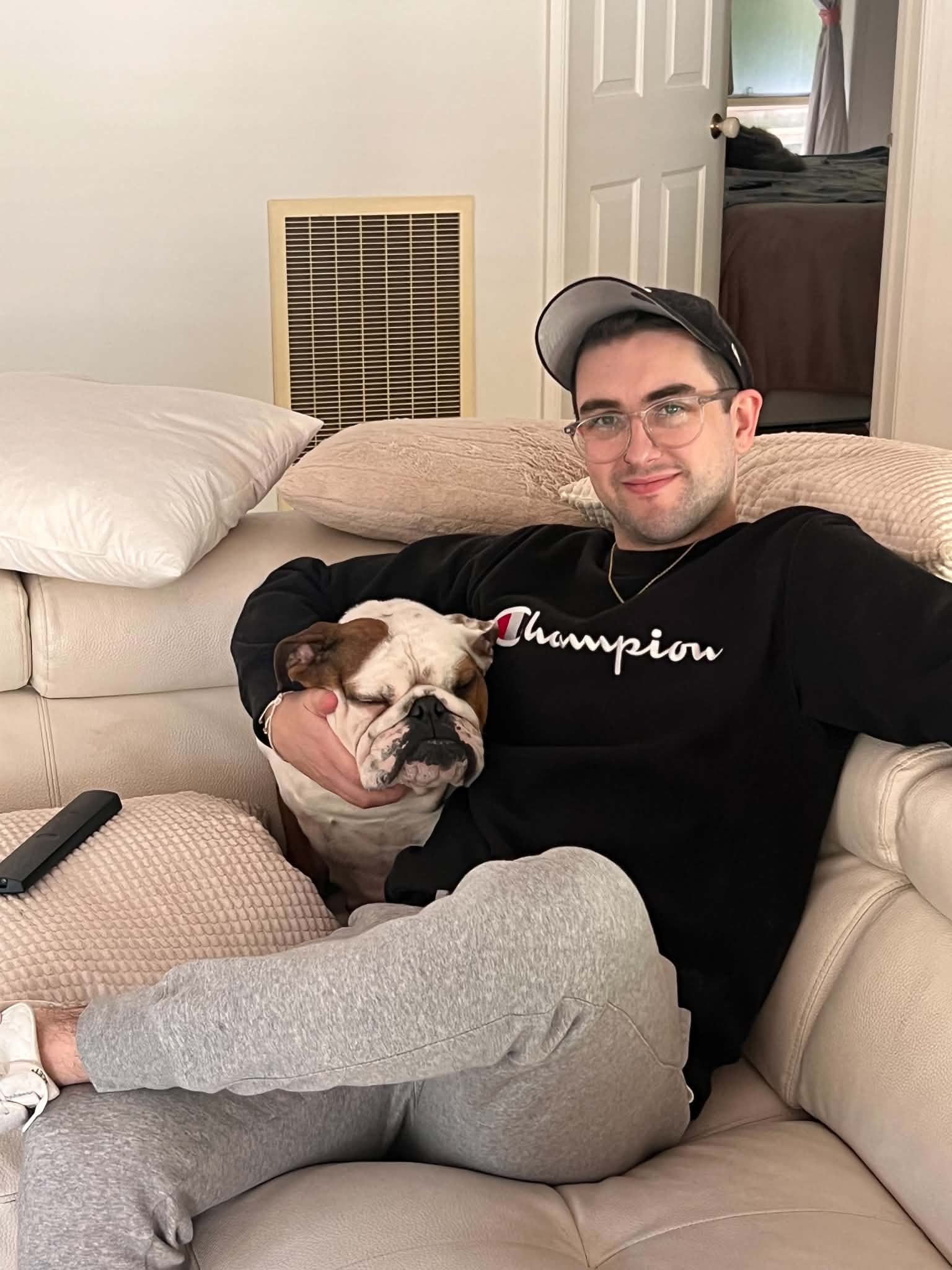 Miles relaxing on a couch with their English bulldog