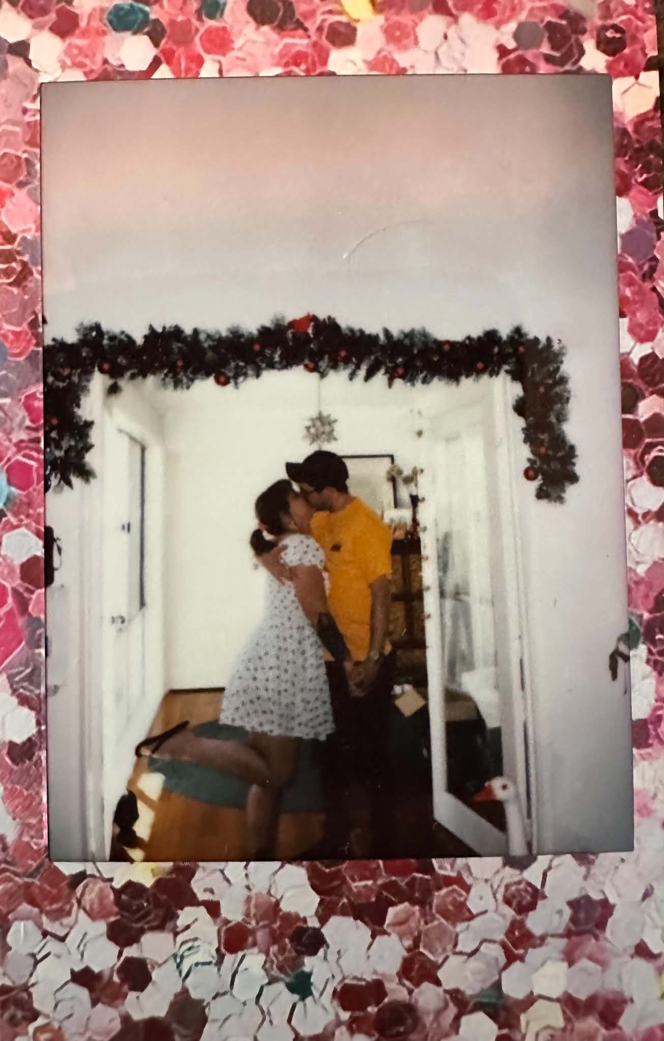 A vintage-style kiss under a string of warm Christmas lights