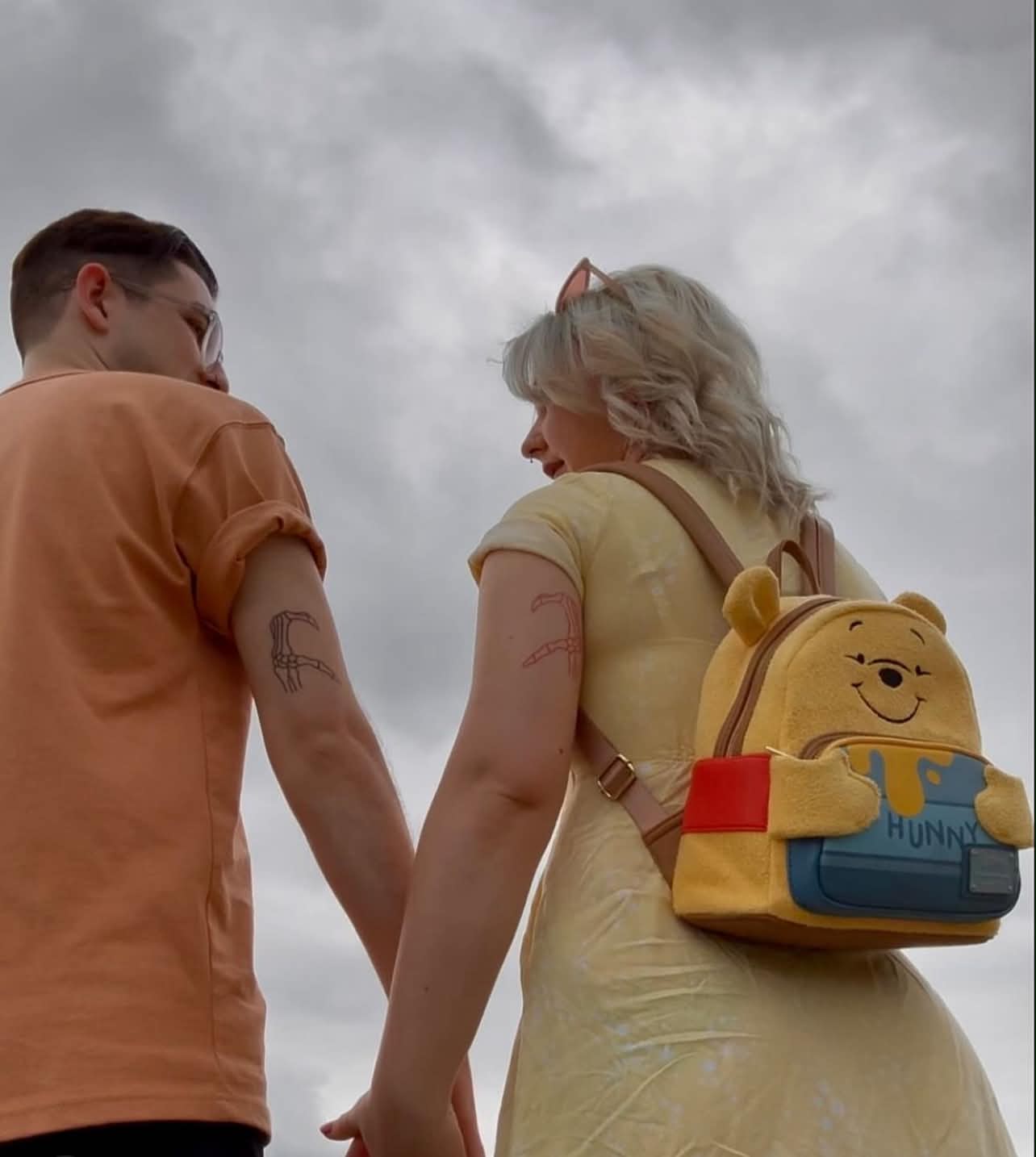 Holding hands, looking up at a cloudy sky